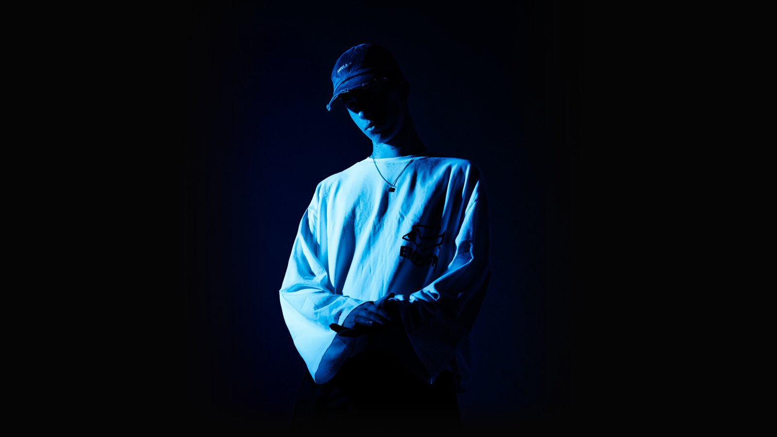 ARLA, wearing a cap with his head lowered, photographed in deep blue light